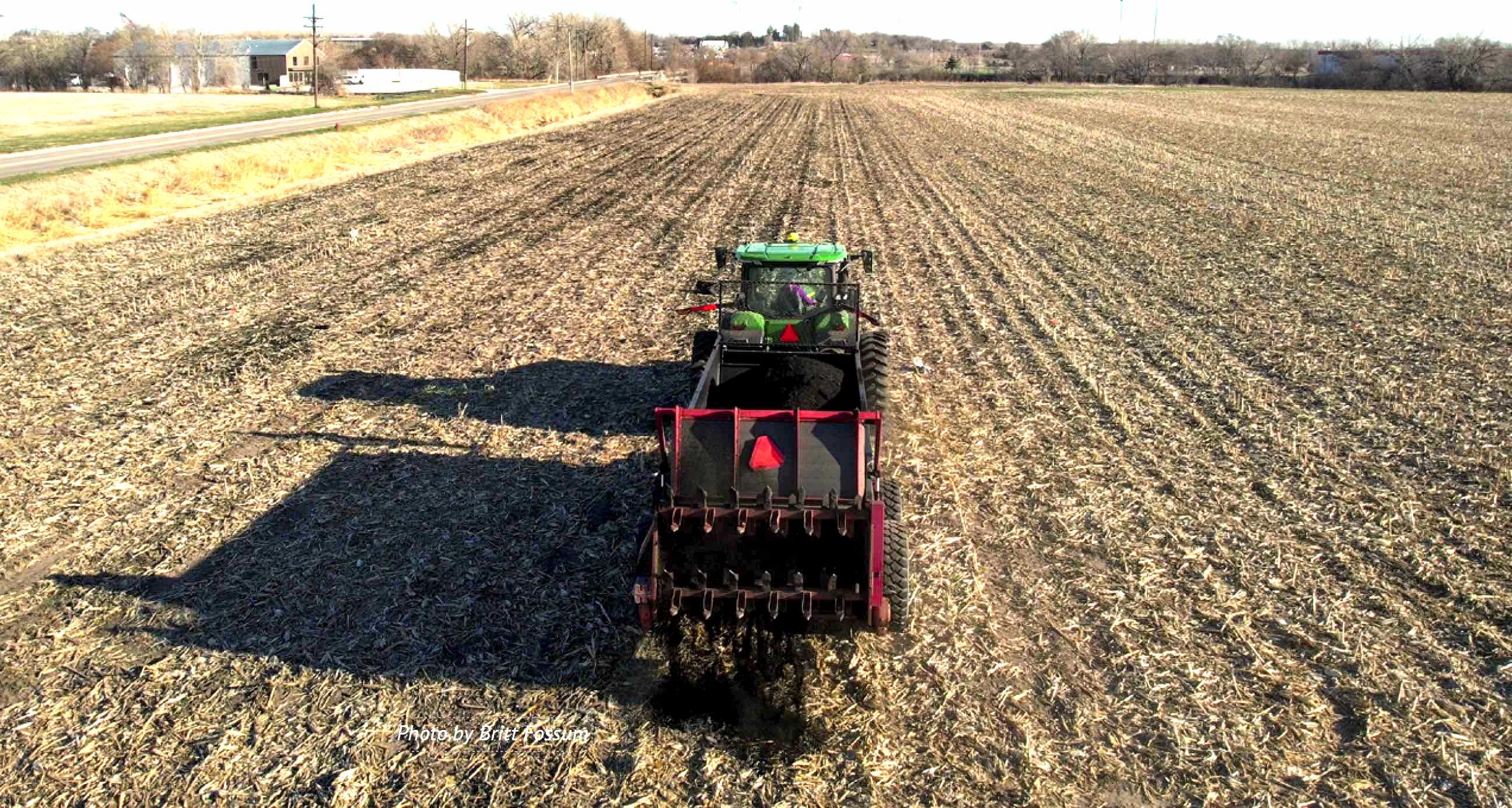 Biochar application by a tractor to open crop field.